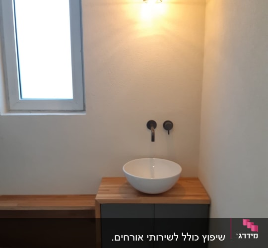 כיור עגול על ארון עץ עם ברז קיר